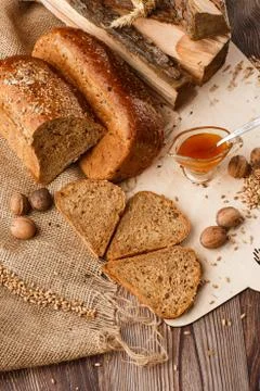 Bread in form of triangle and with nuts and honey near spikelets of wheat lie Stock Photos
