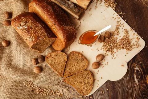 Bread in form of triangle and with nuts and honey near spikelets of wheat lie Stock Photos