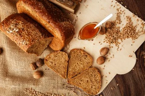 Bread in form of triangle and with nuts and honey near spikelets of wheat lie Stock Photos