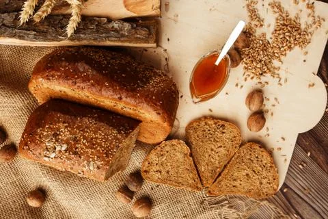 Bread in form of triangle and with nuts and honey near spikelets of wheat lie Stock Photos