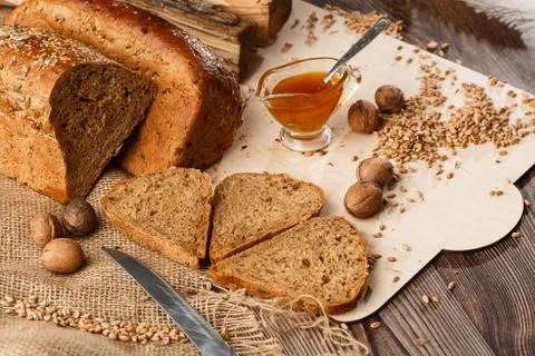 Bread in form of triangle and with nuts and honey near spikelets of wheat lie Stock Photos