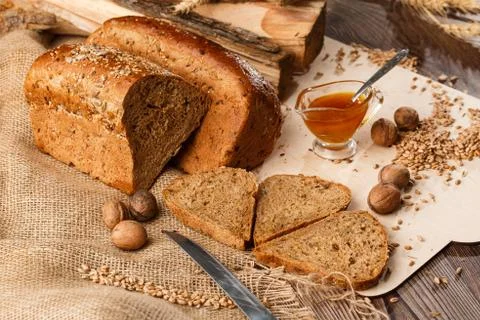 Bread in form of triangle and with nuts and honey near spikelets of wheat lie Stock Photos
