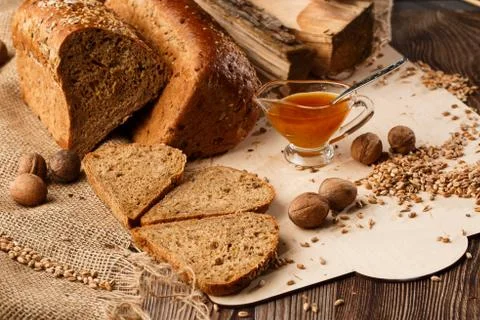 Bread in form of triangle and with nuts and honey near spikelets of wheat lie Stock Photos