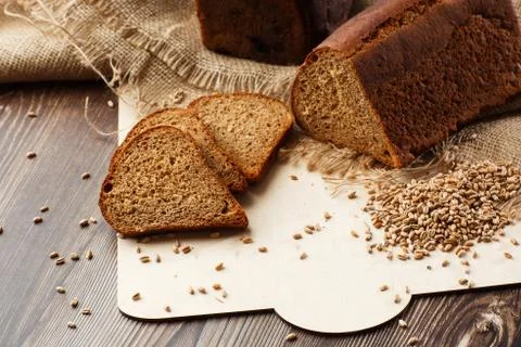 Bread in form of triangle and with sunflower seeds near spikelets of wheat li Stock Photos