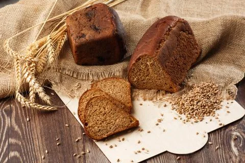 Bread in form of triangle and with sunflower seeds near spikelets of wheat li Stock Photos