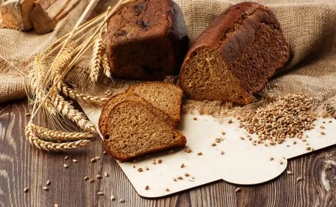 Bread in form of triangle and with sunflower seeds near spikelets of wheat li Stock Photos
