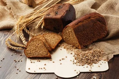 Bread in form of triangle and with sunflower seeds near spikelets of wheat li Stock Photos