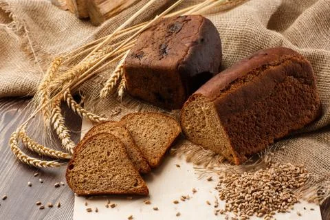 Bread in form of triangle and with sunflower seeds near spikelets of wheat li Stock Photos