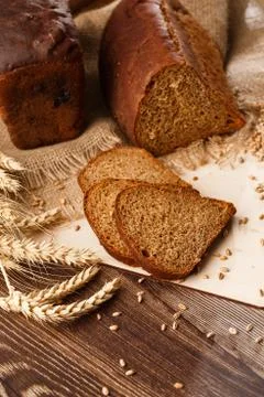 Bread in form of triangle and with sunflower seeds near spikelets of wheat li Stock Photos