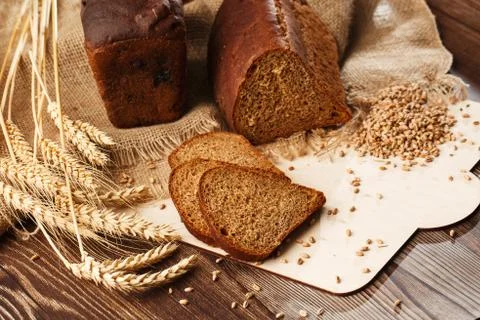 Bread in form of triangle and with sunflower seeds near spikelets of wheat li Stock Photos