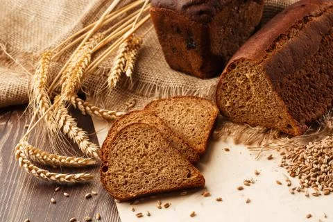 Bread in form of triangle and with sunflower seeds near spikelets of wheat li Stock Photos
