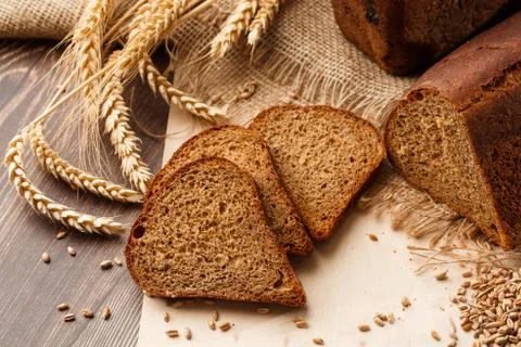 Bread in form of triangle and with sunflower seeds near spikelets of wheat li Stock Photos