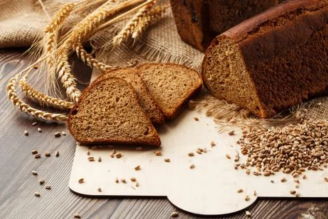 Bread in form of triangle and with sunflower seeds near spikelets of wheat li Stock Photos