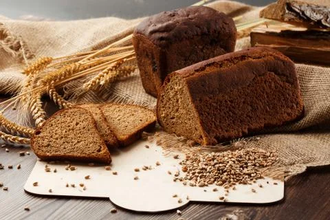 Bread in form of triangle and with sunflower seeds near spikelets of wheat li Stock Photos