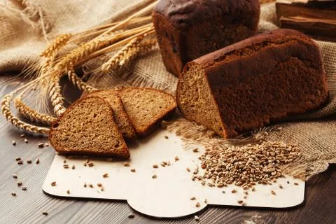 Bread in form of triangle and with sunflower seeds near spikelets of wheat li Stock Photos
