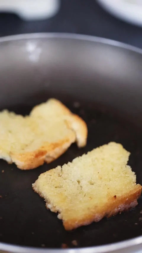 The bread is fried in butter frying pan. Making toast or croutons for break.. Stock Footage 345588761