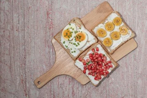 Bread has cream cheese and pomegranate boiled egg banana on red background. Stock Photos