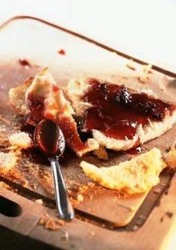 Bread with jam and spoon, on cutting board with crumbs Stock Photos