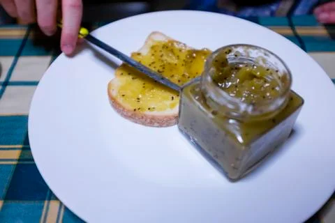 Bread with kiwi jam spread with knife on the kitchen table Stock Photos