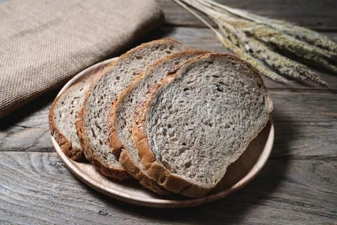 Bread loaf and wheat ears and sack on wooden background. Stock Photos