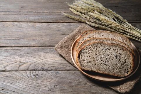 Bread loaf and wheat ears and sack on wooden background. Stock Photos