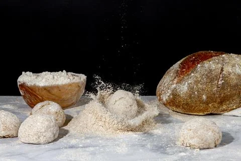 A bread loaf splash on a pile of wholewheat flour on marble countertop Stock Photos