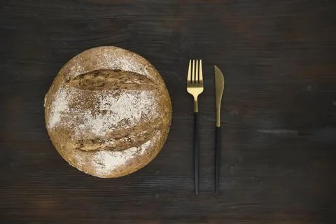 Bread loaf viewed from above. Bread over a wood background with golden cutlery. 스톡 사진
