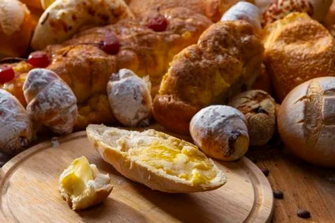 Bread with melted butter and various artisan breads on a wooden table. Stock Photos