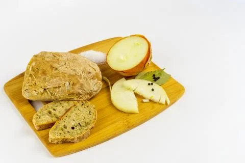 Bread, onion, salt, pepper and bay leaves on a wooden board. Stock Photos