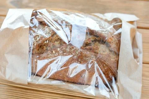 Bread in a paper bag. Transparent packaging. Side view, wooden background Foto stock