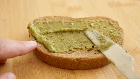 Bread with pesto sauce. Hand spreading sauce on bread with knife. Sandwich Stock Footage 315177325