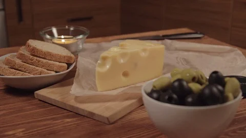 Bread, piece of cheese, and olives in a white bowls Vidéo 73919448