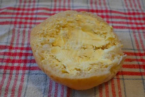 Bread roll with butter on checkered cloth Stock Photos