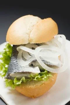 Bread roll filled with herring and onions on paper napkin Stock Photos