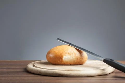 Bread roll with knife on plate Stock Photos