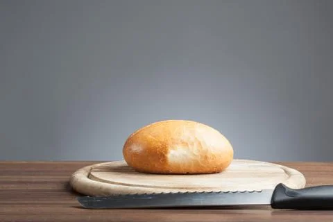 Bread roll with knife on plate Stock Photos