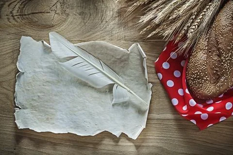 Bread rye ears red polka-dot tablecloth feather vintage sheet on wooden board 스톡 사진