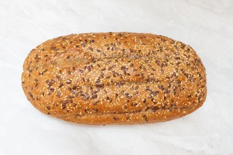 Bread with seeds on the table. Flat lay. Top view. Marble countertop. Stock Photos