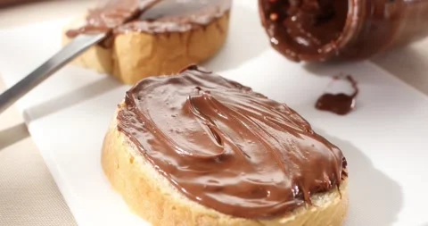 Bread slice with chocolate hazelnut spread or butter. Angle view. Slow motion. Stock Footage 242506602