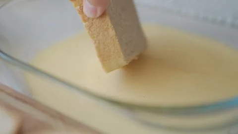 Bread slice is dipped into egg mixture in glass bowl Stock Footage 341273616