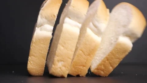 Bread slice falling in slow motion on black table Stock Footage 142485634