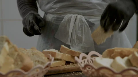 Bread is sliced in a kitchen for a food donation event at a local shelter in Stock Footage 345147257