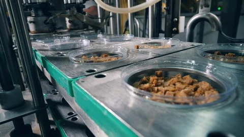 Bread snacks in plates are getting closed with foil pieces. Packing process at Stock Footage 115106160