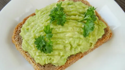 Bread spread with avocado on a plate. Video stock 247392069