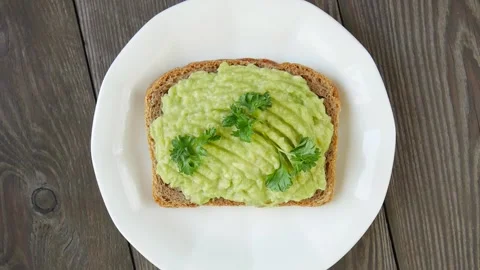 Bread spread with avocado on a plate. Video stock 247483891