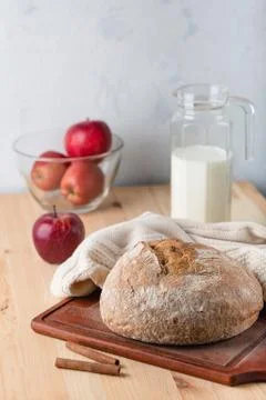 Bread on a table made of wood. Red apples and milk jug. 스톡 사진