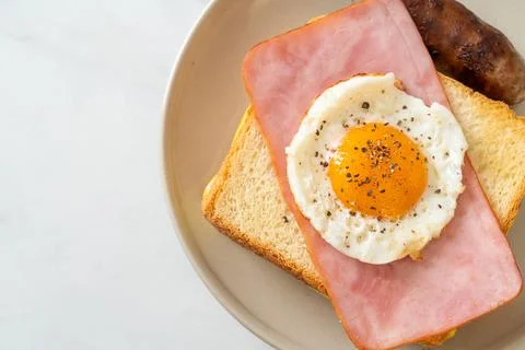 Bread toasted cheese topped ham and fried egg with pork sausage Stock Photos