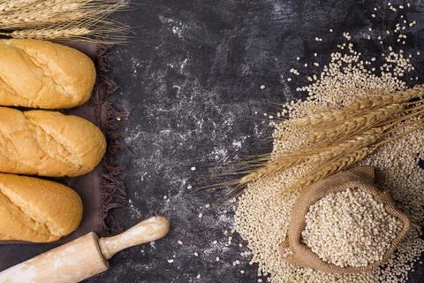 Bread with wheat ears and wheat grains in a sack Placed on a dark black board Stock Photos