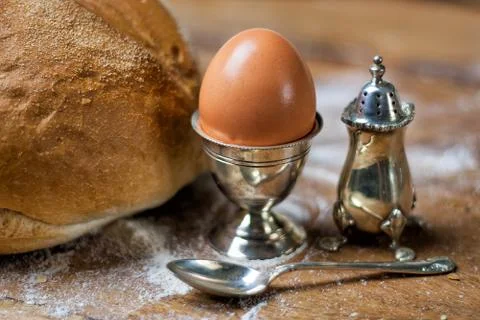 Bread on the wooden table with flour, egg in silver vintage utensil, salt shaker Stock Photos