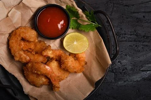 Breaded and breaded shrimp with chilli sauce on black background Foto stock